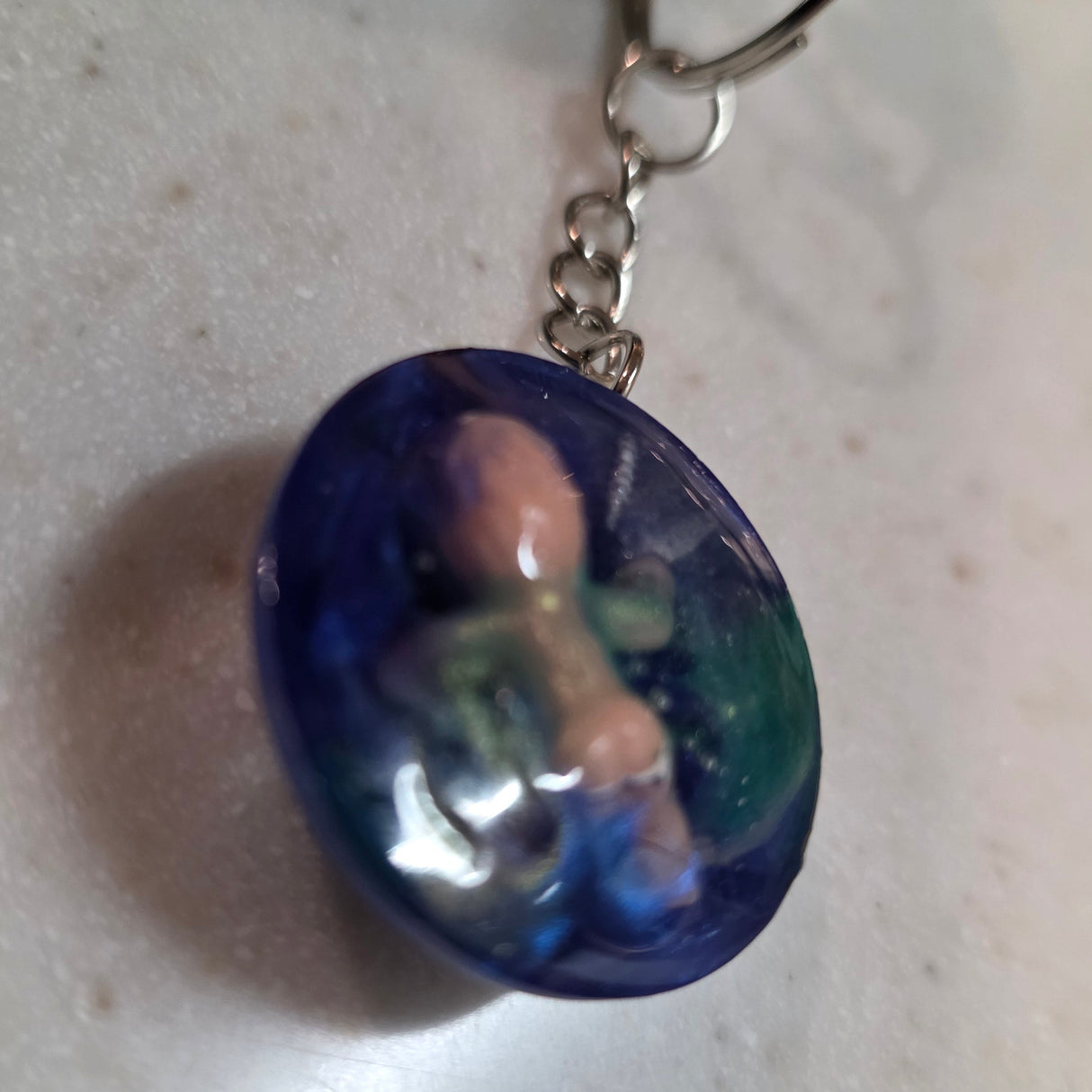 Keychain with a blue oval pendant on a light gray surface