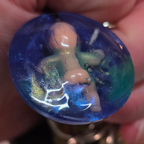 Hand holding a creepy bsby blue marbled keychain