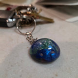 Keychain with a blue and green marbled charm on a light surface