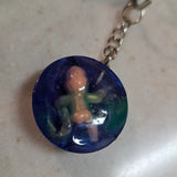 Blue round pendant a on a chain against a light background