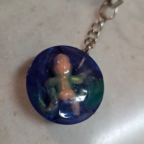 Blue round pendant a on a chain against a light background