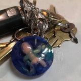 Keychain with a blue round charm featuring a cute/creepy baby person on a white background