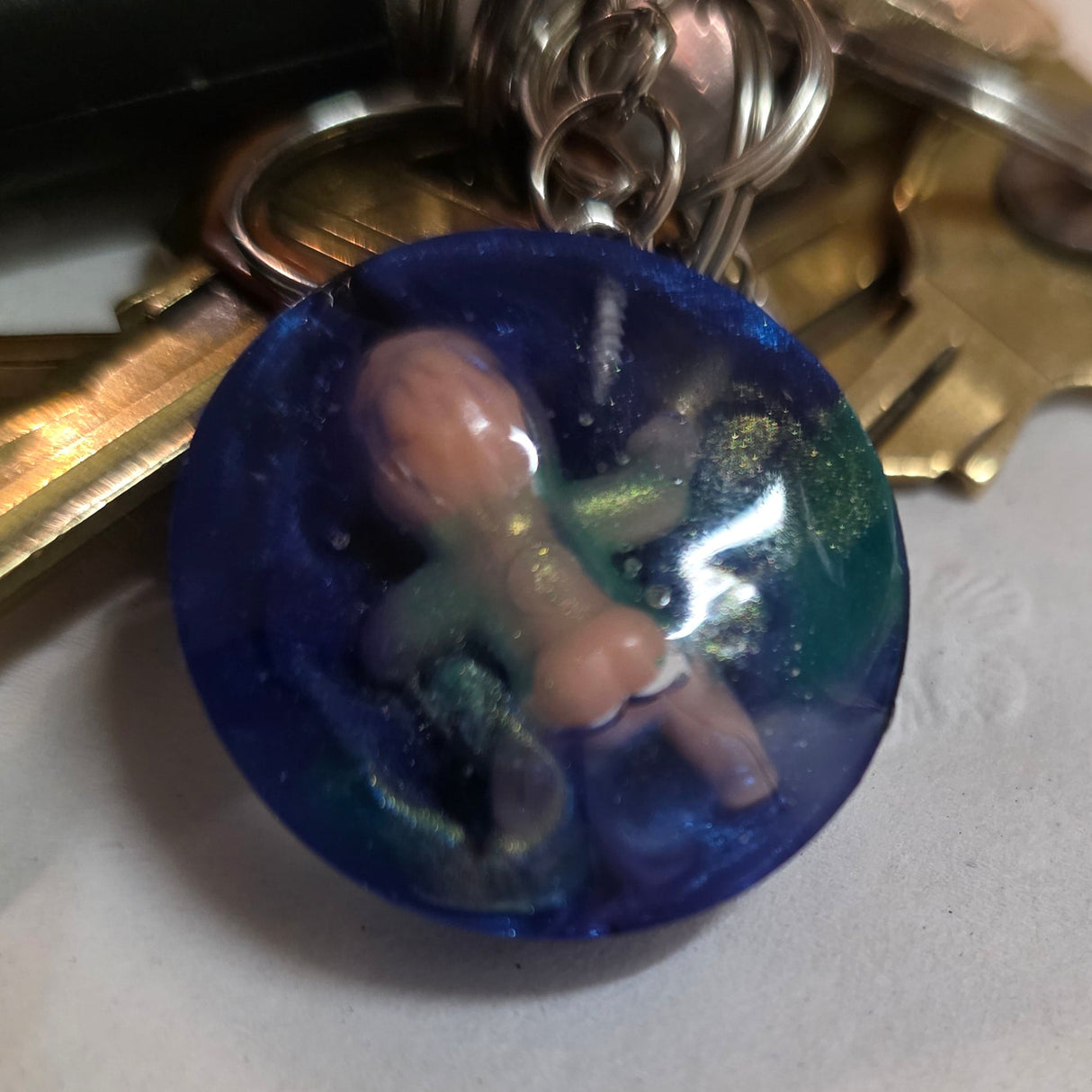 Keychain with a blue charm featuring a small figurine on a textured surface
