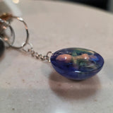 Keychain with a blue green resin trapped cute creepy baby featuring its backside and bum showing 