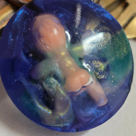 Creepy or cute baby in a resin blue base keychain on a white surface