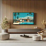 A framed art print depicting a retro mid-century modern poolside house with palm trees and mountains, displayed on a slatted wood wall in a modern living room setting.