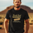 A man standing in a desert setting, wearing a black T-shirt with a retro graphic that says 'Barely Used Bandages'.