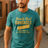 A man standing in a desert setting, wearing a blue T-shirt with a retro graphic that says 'Barely Used Bandages'.