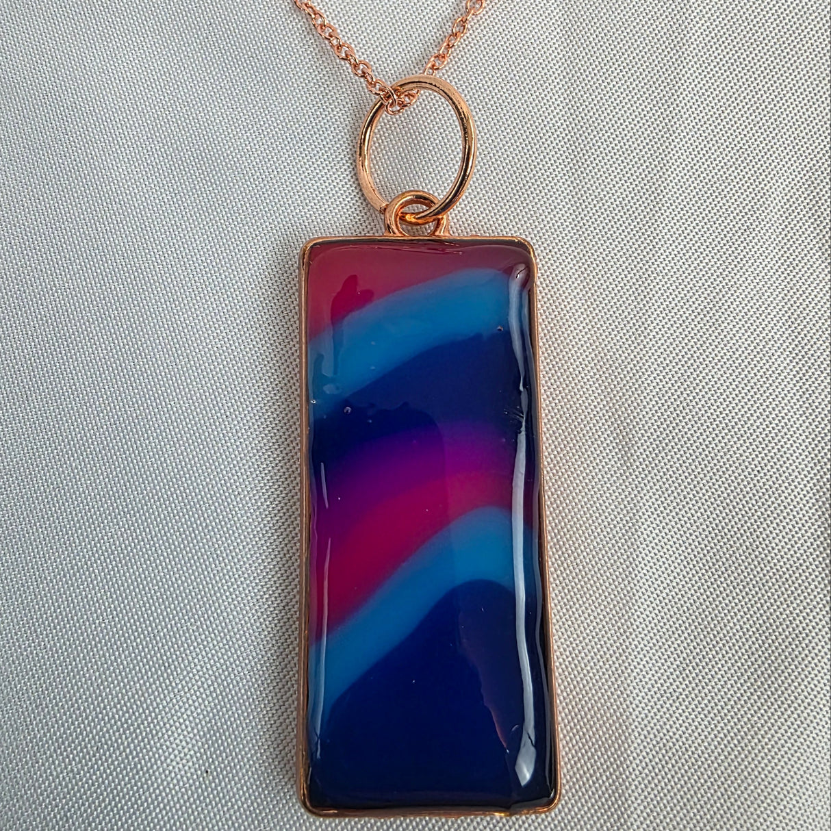 Necklace with a rectangular pendant featuring blue and pink colors on a light gray background
