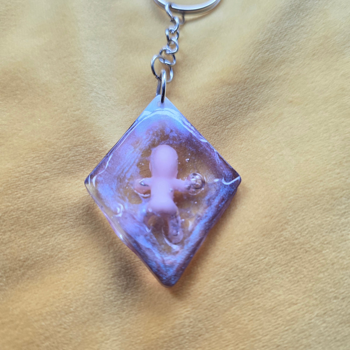 Keychain with a small figurine inside a clear cube on a beige background