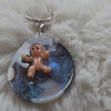 Keychain with a baby on a blue background, placed on a fluffy white surface.